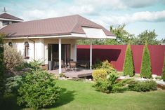 the house is surrounded by trees and shrubs, with a covered patio area on one side