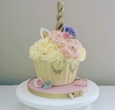 a cupcake decorated with pink, white and blue flowers on top of a cake stand