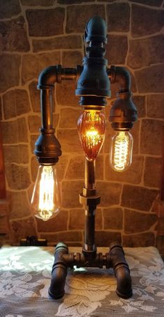 three light bulbs are attached to an old fashioned lamp on a table with a stone wall in the background