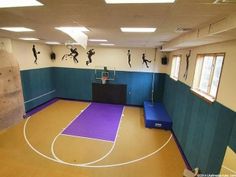 an indoor basketball court with blue walls and purple mats on the floor is pictured in this image