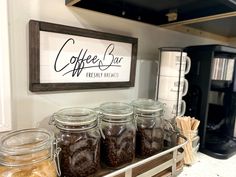 there are many jars with coffee beans in them on the shelf next to an espresso machine