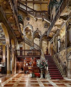 an ornately decorated lobby with staircases and potted plants on the table in front of it