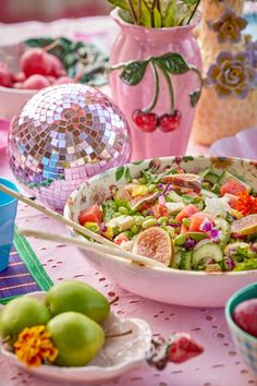 a table topped with lots of different types of food and vases filled with flowers