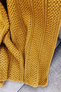 a yellow knitted blanket sitting on top of a couch