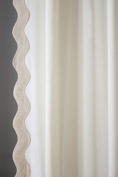 a white curtain hanging on the side of a window