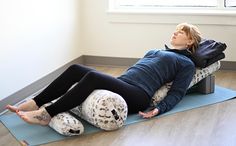 a woman laying on top of a blue mat in a room next to a window