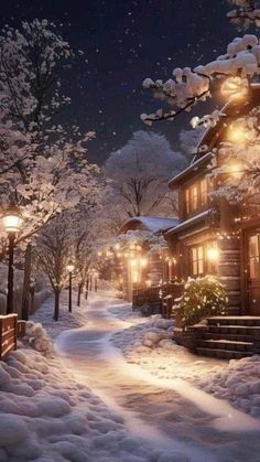 a snow covered street at night with lights on the buildings and trees in the foreground