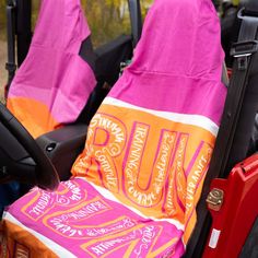 two pink and orange towels sitting on the back of a car