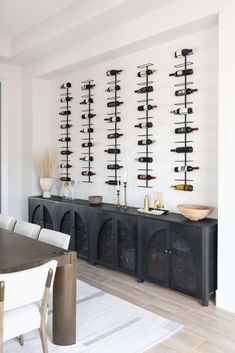 a dining room table and chairs with wine racks on the wall