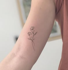 a woman's arm with a small flower tattoo on the left side of her arm