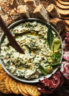 a bowl of dip surrounded by crackers and bread