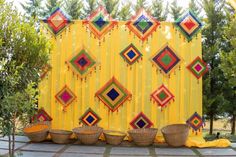 colorfully decorated wall with baskets on the side and trees in the backgroud