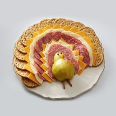 a platter with crackers, cheeses and meats on it next to an apple