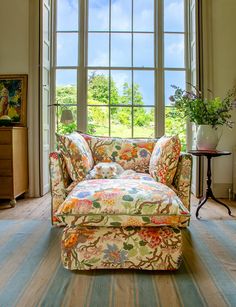 a living room with a floral couch and large windows