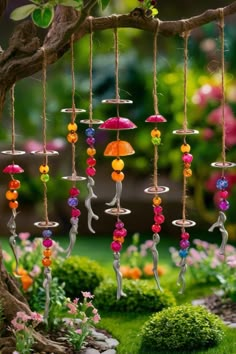 a wind chime hanging from a tree filled with colorful beads and umbrellas in a garden