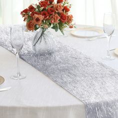 an elegant table setting with orange flowers and wine glasses