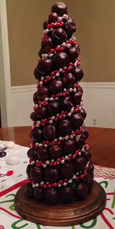 a christmas tree made out of chocolate covered donuts on a table with red and white beads