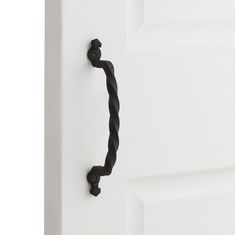 a black door handle on the side of a white door with an ornate knot design