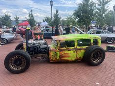 an old hot rod car is painted yellow and green with rust on it's hood