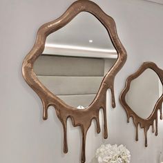 a mirror that is hanging on the wall next to a vase with flowers in it