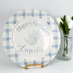 a blue and white checkered plate next to a vase with tulips