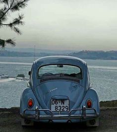 an old blue car parked by the water