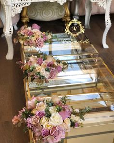 three glass boxes with flowers in them sitting on the floor next to a mirror table