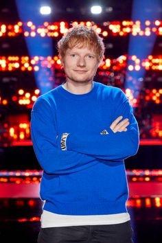 a man in a blue sweater is standing with his arms crossed