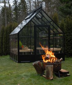 a fire pit sitting in the middle of a yard next to a small house with a glass roof