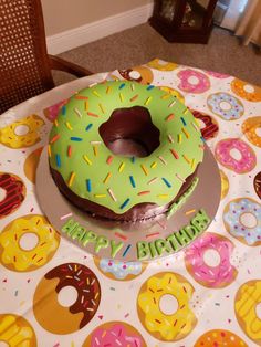 a green frosted doughnut sitting on top of a table covered in sprinkles