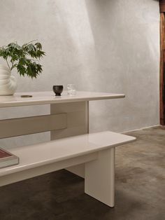 a white table with a vase and book on it