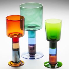 three different colored glass vases sitting next to each other