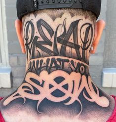 the back of a man's head with tattoos on it and letters all over his neck