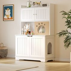 a dog house is in the corner of a room with a potted plant and pictures on the wall