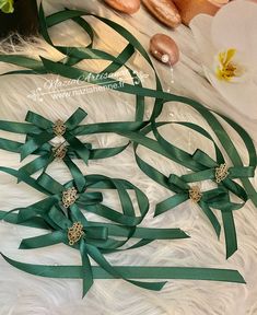 green satin ribbon with crystal stones and pearls in center on white fur, surrounded by flowers