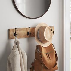 a hat, coat rack and mirror hanging on a wall next to a purse bag