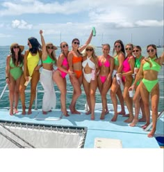 a group of women standing on top of a boat in bikinis and sun glasses