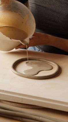 a person pouring something into a bowl on top of a table