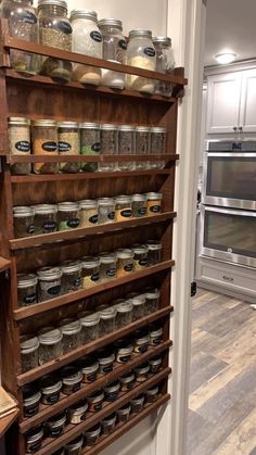 an old wooden spice rack with jars and spices on it's shelves in a kitchen