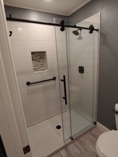 a white toilet sitting next to a shower in a bathroom on top of a hard wood floor