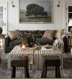 a living room filled with furniture and a painting on the wall above it's coffee table