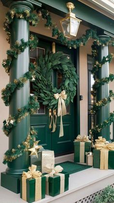 christmas wreath and presents are on the front steps of a house with green pillars, gold bows and lights