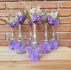 four vases with flowers in them are sitting on a wooden table next to a brick wall