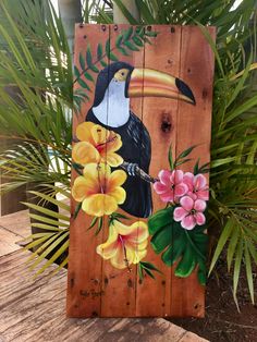 a wooden sign with a toucao and flowers painted on it's side