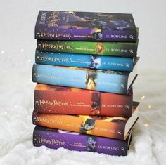 a stack of harry potter books sitting on top of a pile of white fluffy blankets