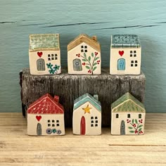 four small houses are sitting on top of a wooden block, each painted with different designs