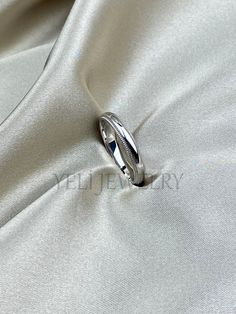 a wedding ring is shown on top of a white satin material fabric, with the background visible