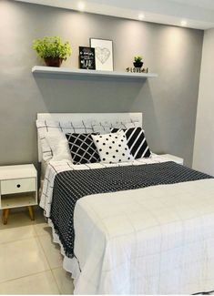 a white bed with black and white pillows on it's headboard in a bedroom