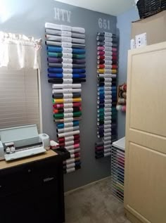 there is a sewing machine in front of two wall racks with different colored spools on them