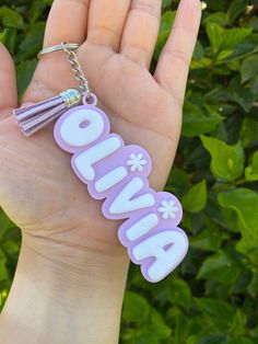 a hand holding a purple and white keychain with the word avana on it